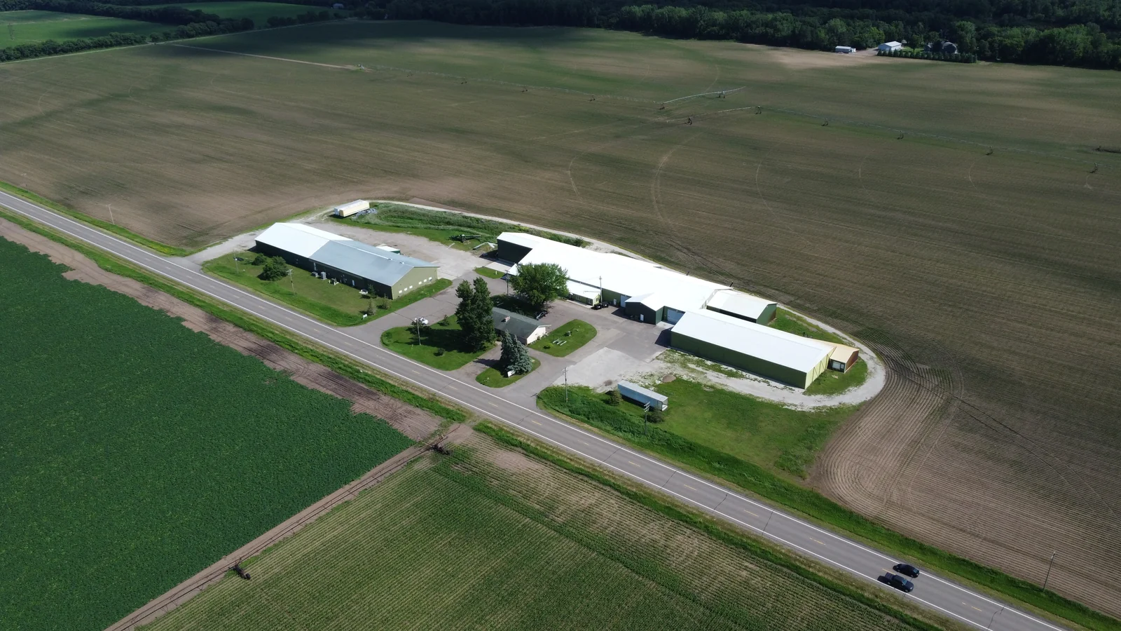 Aerial view of a long agricultural building with a silver standing seam metal roof on a farm in Aitkin, MN