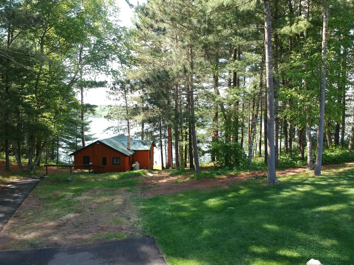 Aerial view of a wooded lakeside cabin with an evergreen green standing seam metal roof in Brainerd, MN