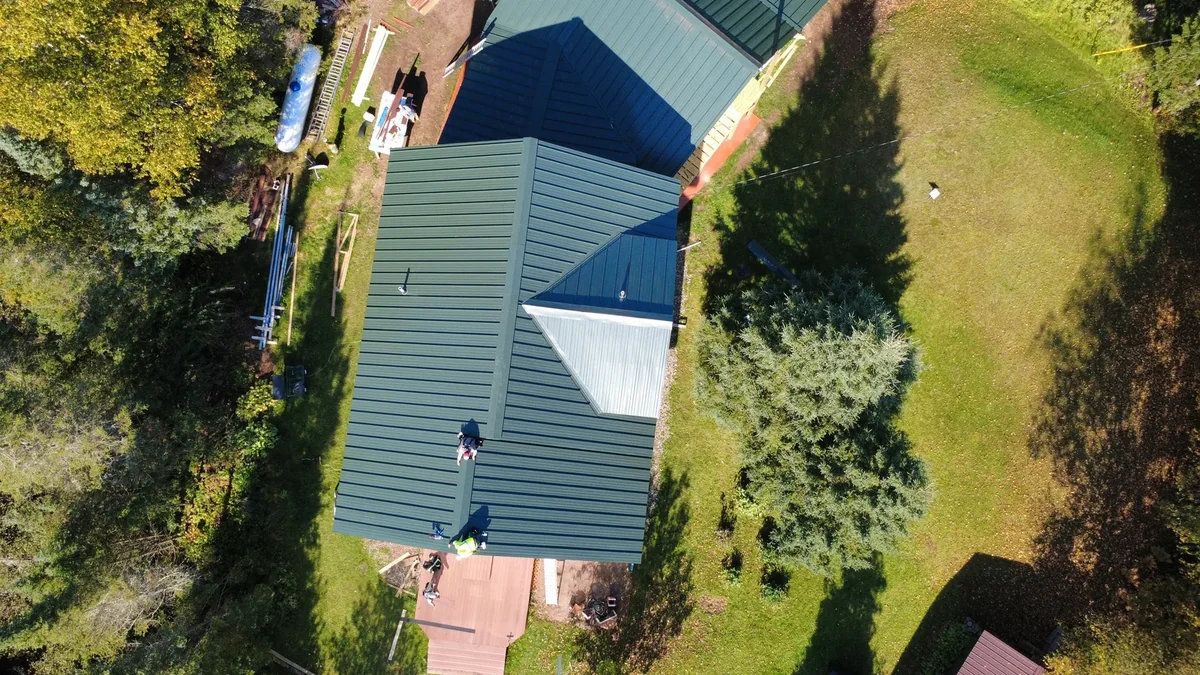 Overhead angle of the blue standing seam roof showing the ridge lines and dormer.