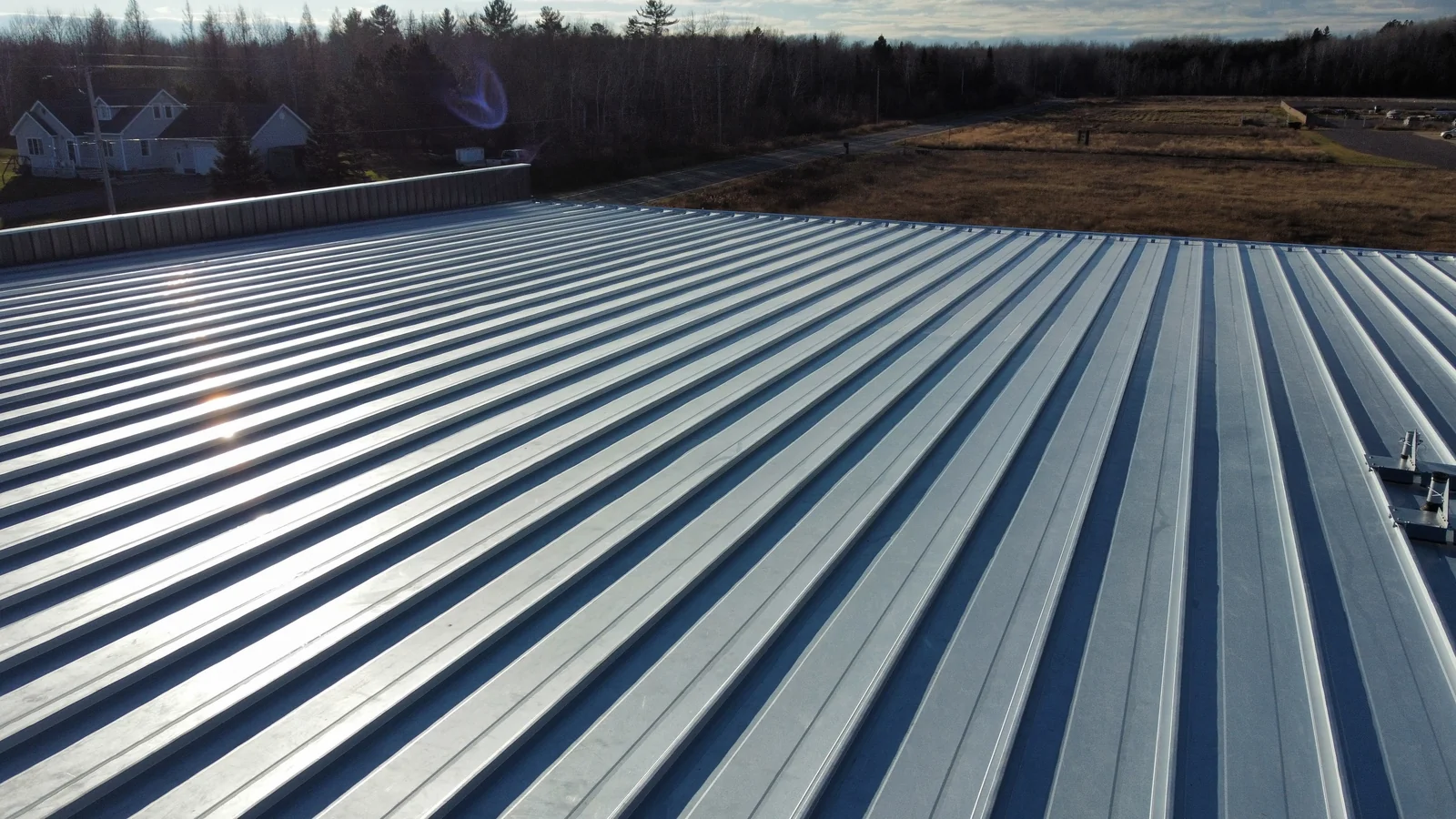Wide aerial view of a sprawling blue standing seam metal roof on a commercial building in Cloquet, MN