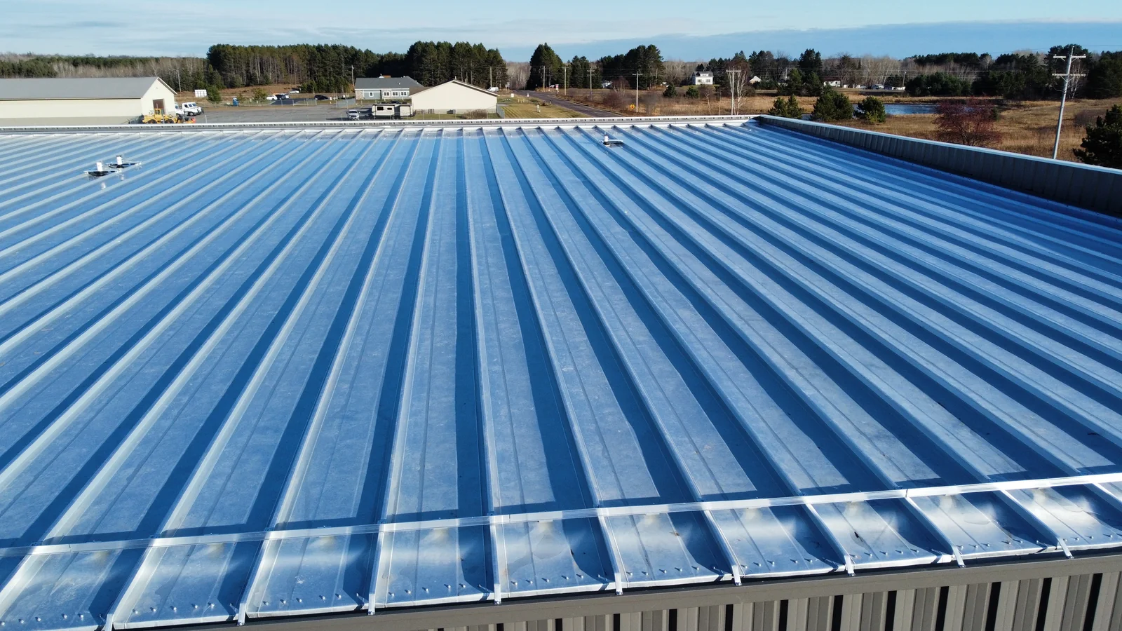 Drone shot of the long blue metal roof panels running the full length of the warehouse