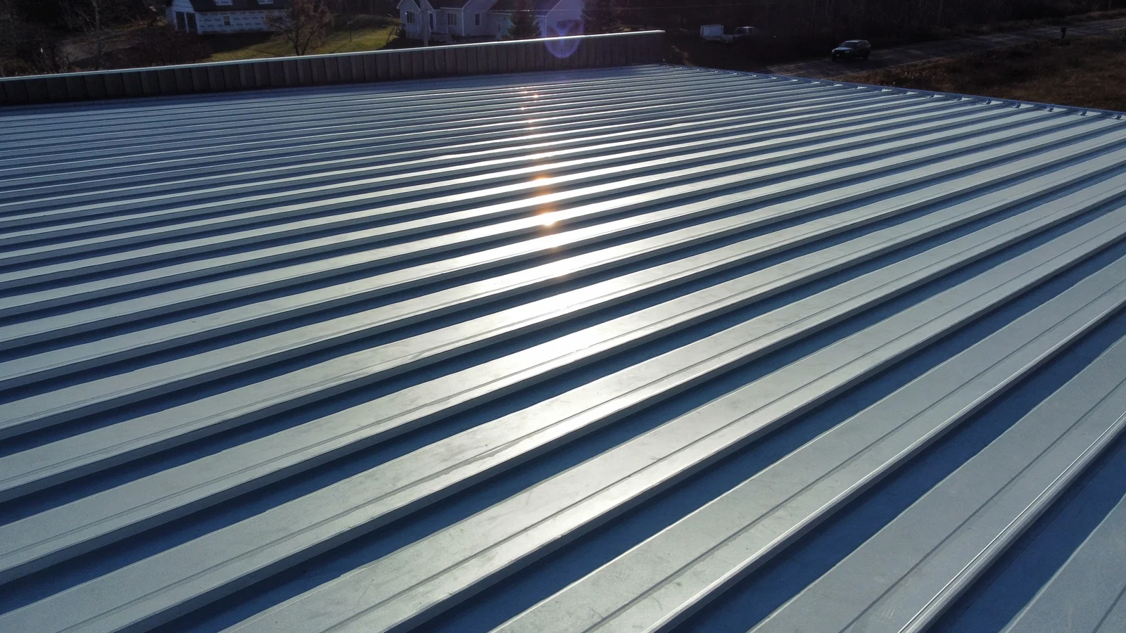 Angled view across the blue metal roof with surrounding fields in the background