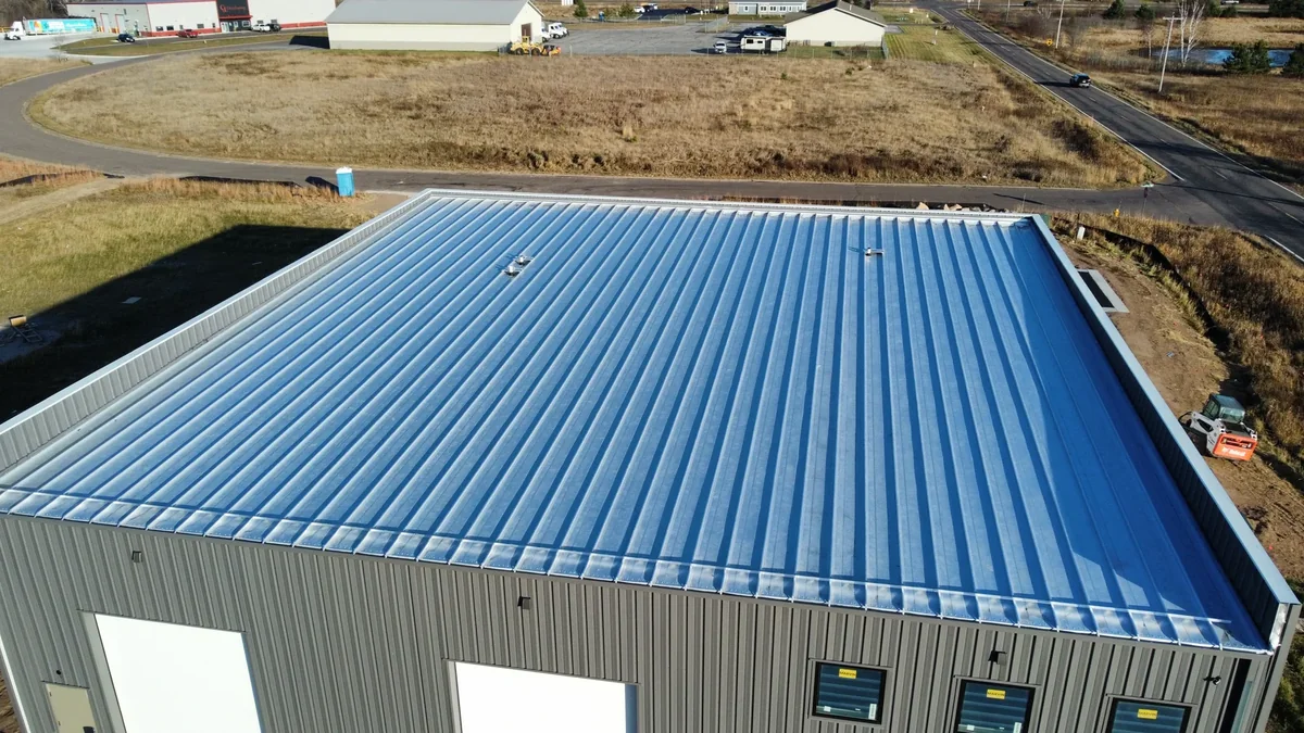 Corner perspective of the blue roof meeting the metal-clad exterior wall