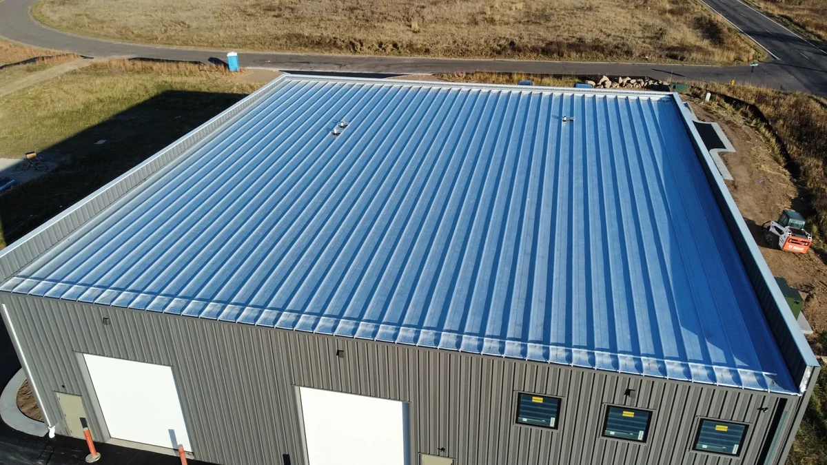 Ground-to-roof view of the steel building showing the blue roof and bay doors below