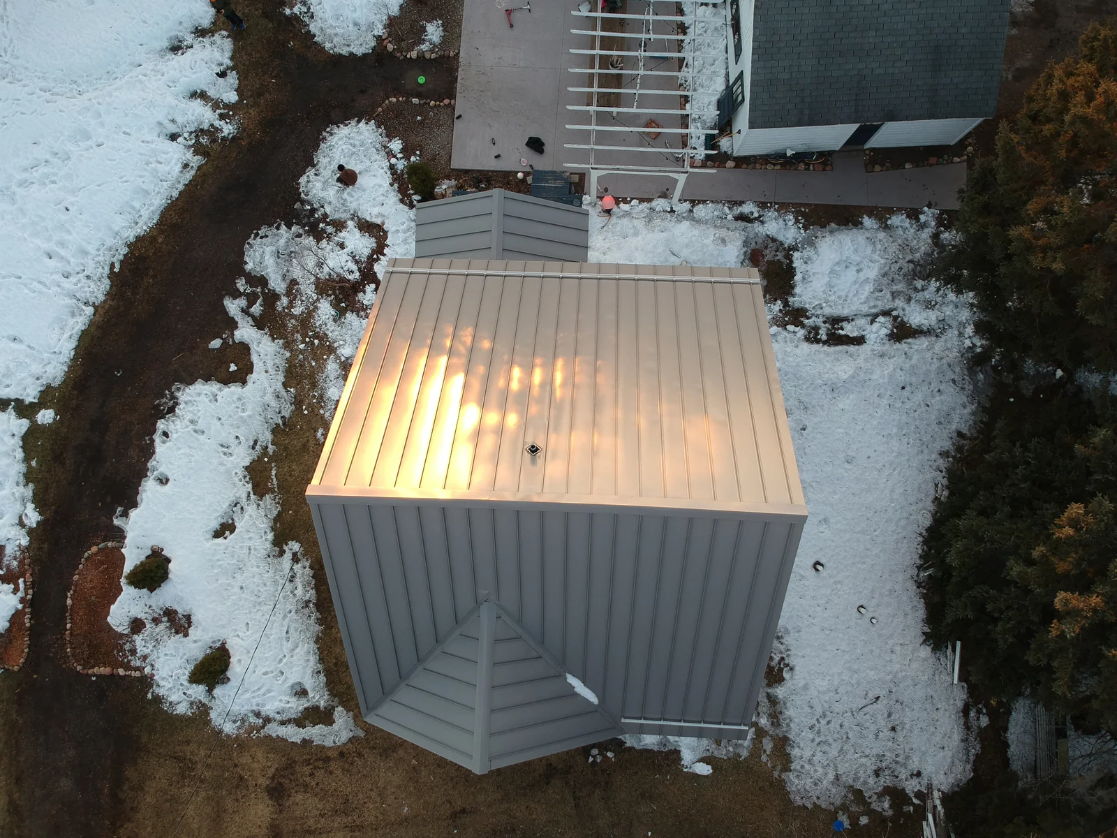 Wide view of the property and detached metal-roofed garage across the snow-covered yard.