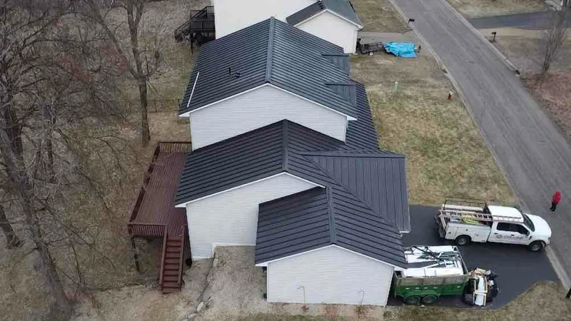 Overhead view of a complex multi-gable charcoal metal roof on a suburban house