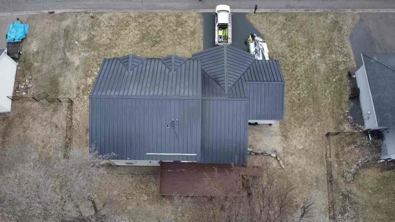 Top-down aerial of the dark gray standing seam roof showing crisp ridge and valley lines