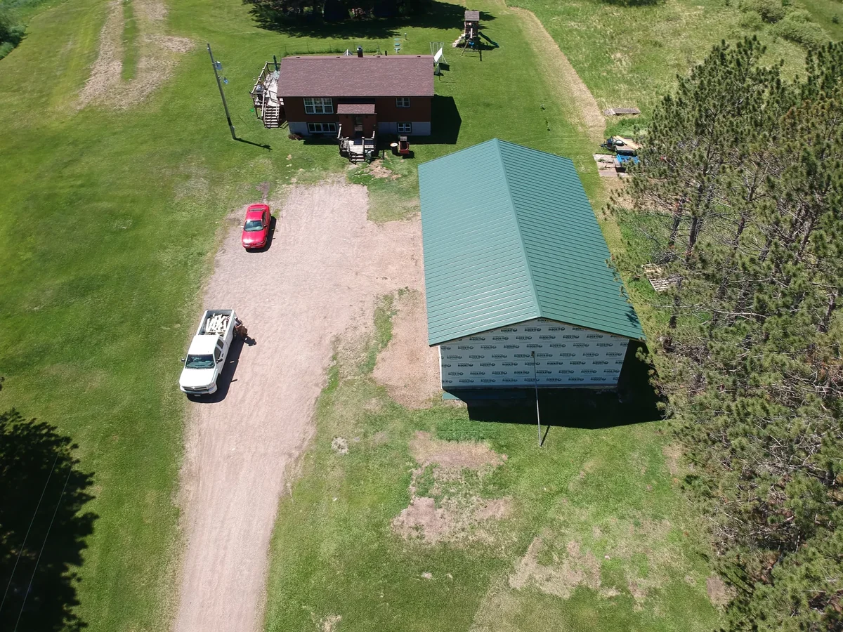 Two structures on the rural property, the larger one topped with the new green metal roof.
