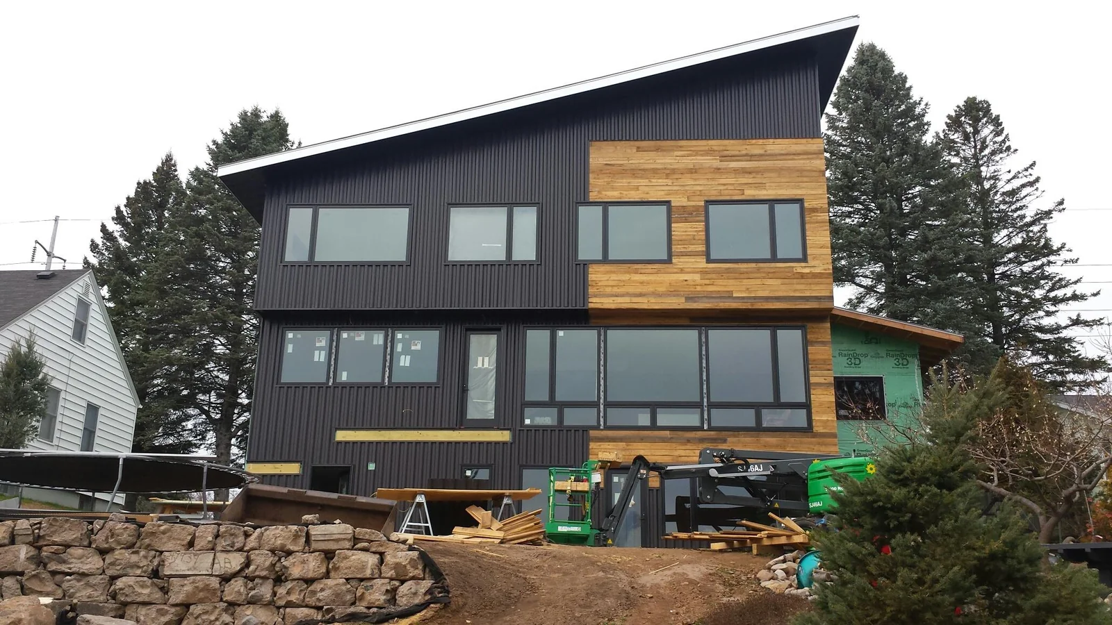 Modern home in Duluth, MN with dark metal siding, wood accents, and a white standing seam metal roof