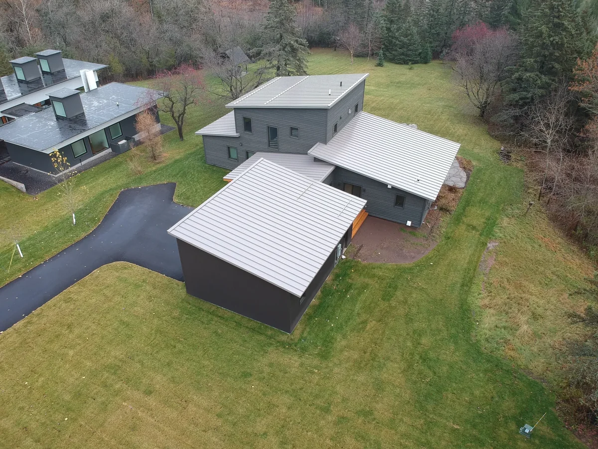 Aerial view of a modern flat-roofed home with a light gray standing seam metal roof in Duluth, MN.
