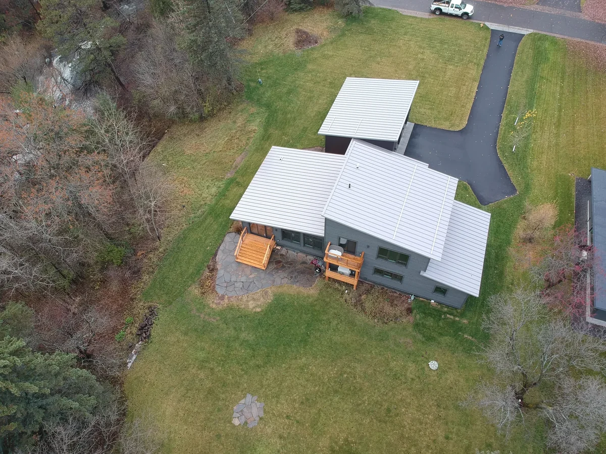 Wide angle showing the modern house and driveway with Lake Superior in the distance.