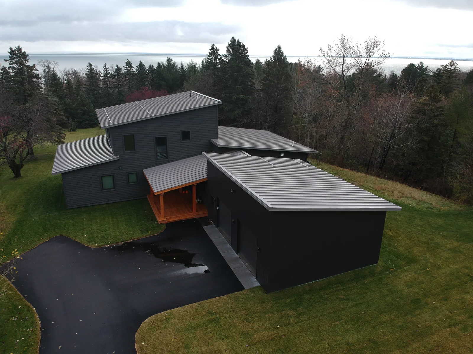 Elevated view of the full home with its gray metal roofing set against the wooded hillside.