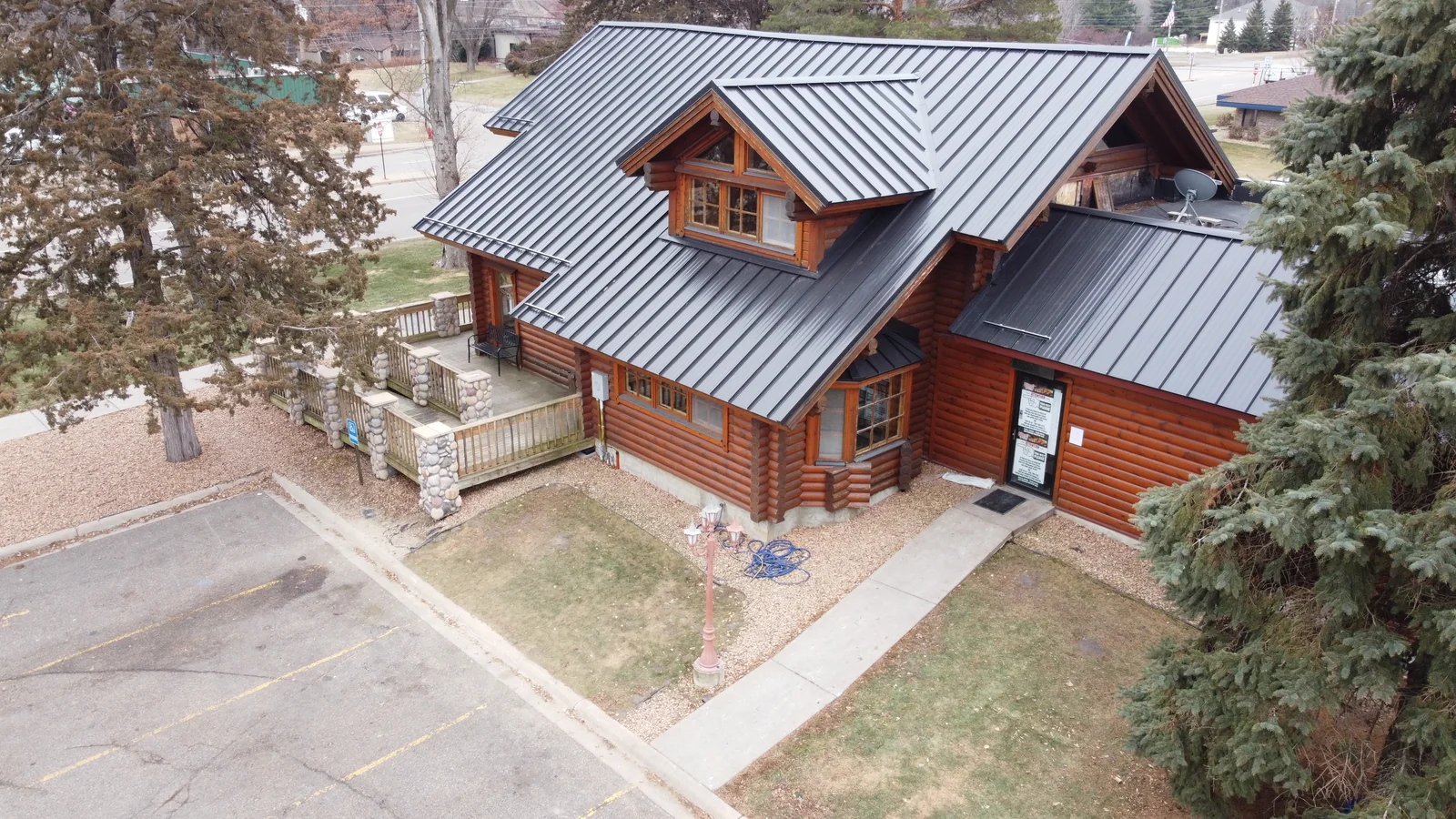 Aerial view of a log-sided commercial lodge with a gray standing seam metal roof in Eagan, MN