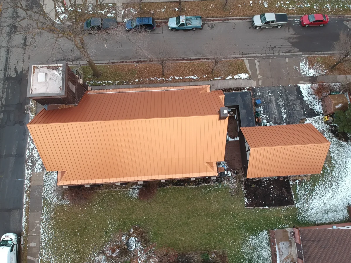 Overhead view emphasizing the gabled copper roof and its ridge line against neighboring rooftops.