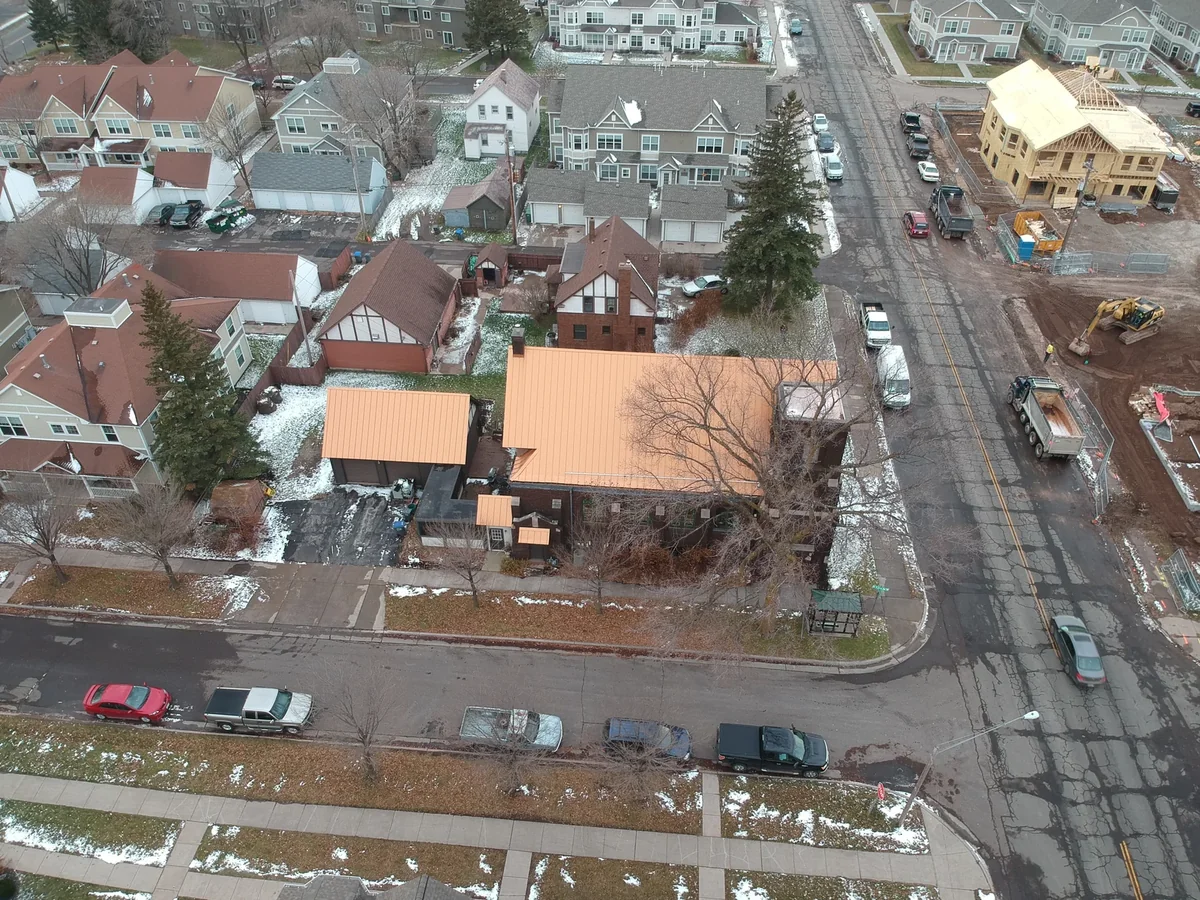 Copper standing seam roof seen from above with parked cars and bare winter trees lining the block.