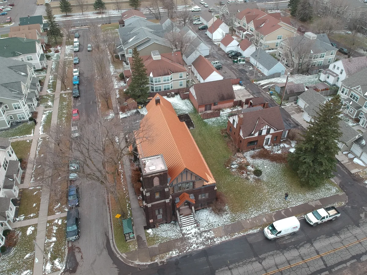 Wide aerial of the copper-roofed building within its surrounding residential neighborhood.