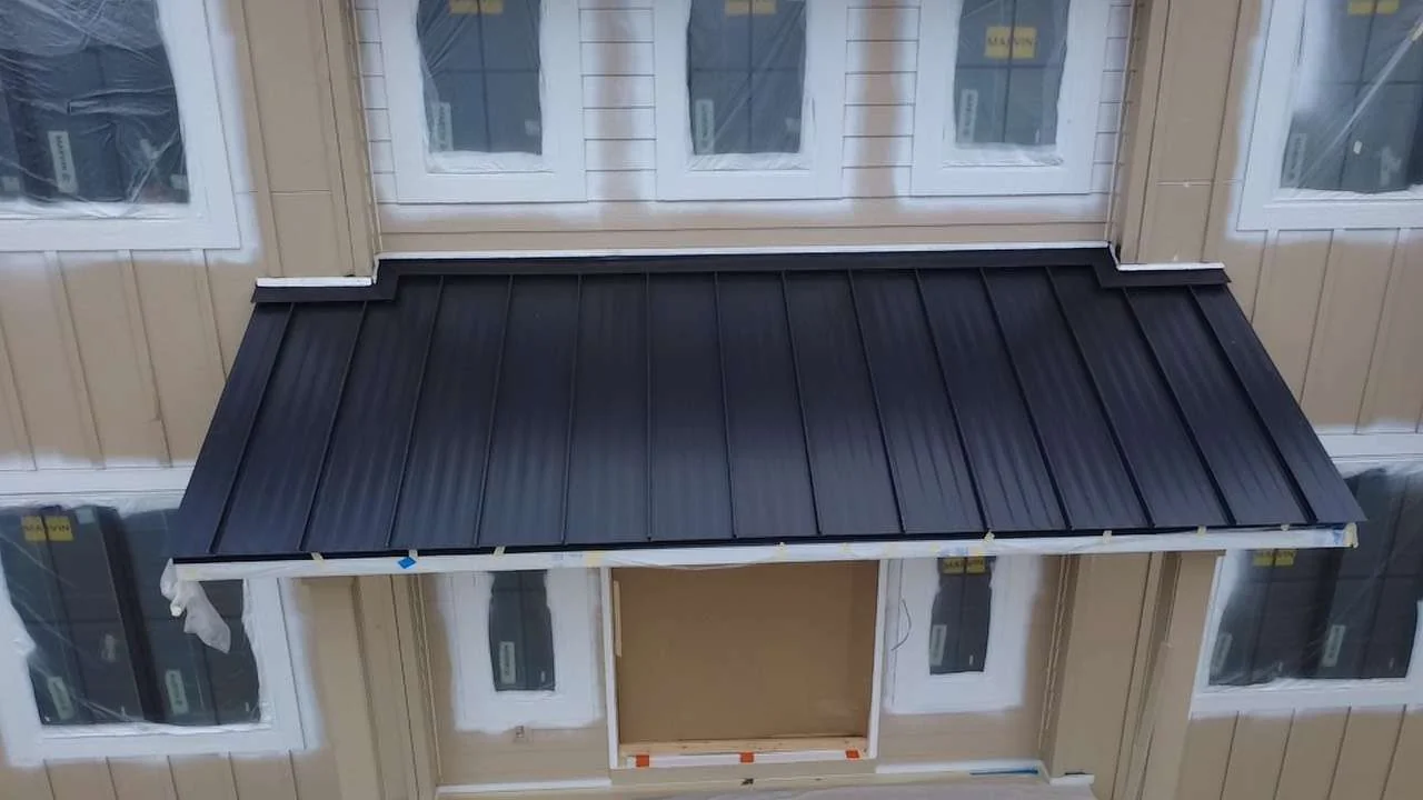 Charcoal standing seam metal roof sheltering a bay window feature on the front facade