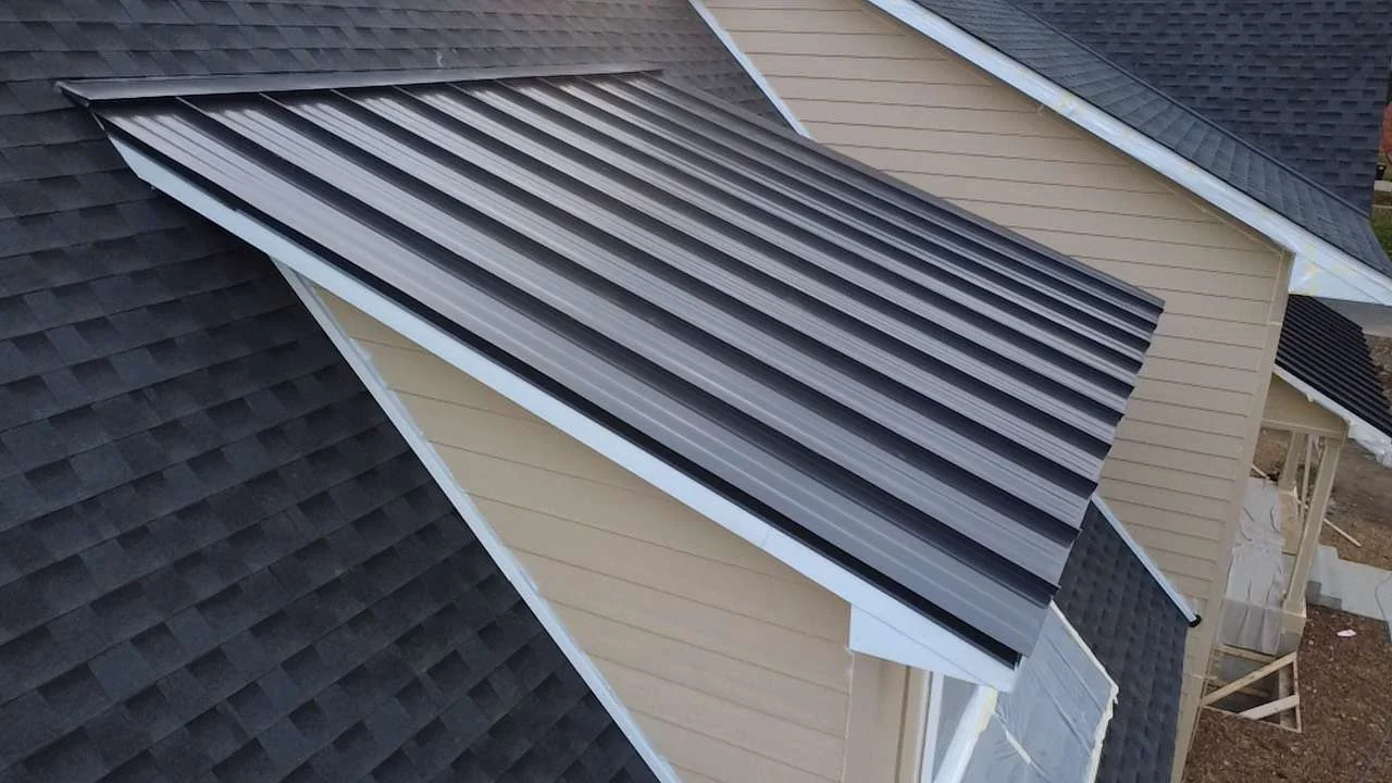Close-up of the dark metal standing seam panels meeting the shingled main roof