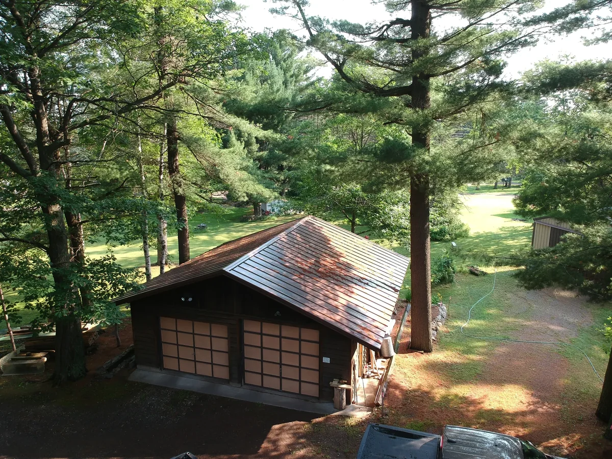 Cabin nestled in the pine forest with its brown metal roof visible through the canopy
