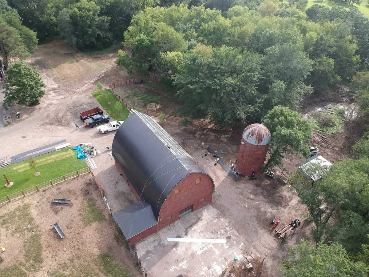 High overview of the long arched barn and silo across the rural property
