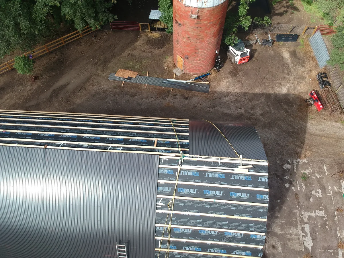 Side aerial of the finished charcoal standing seam panels sweeping over the curved roof