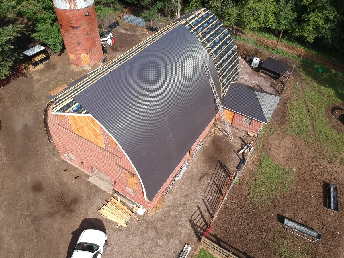 Angled aerial of the gray metal roof running the full length of the barn