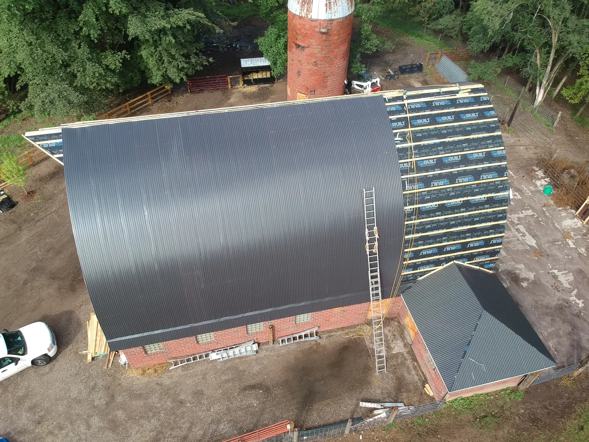 In-progress shot revealing exposed roof decking and purlins beside the brick gable wall