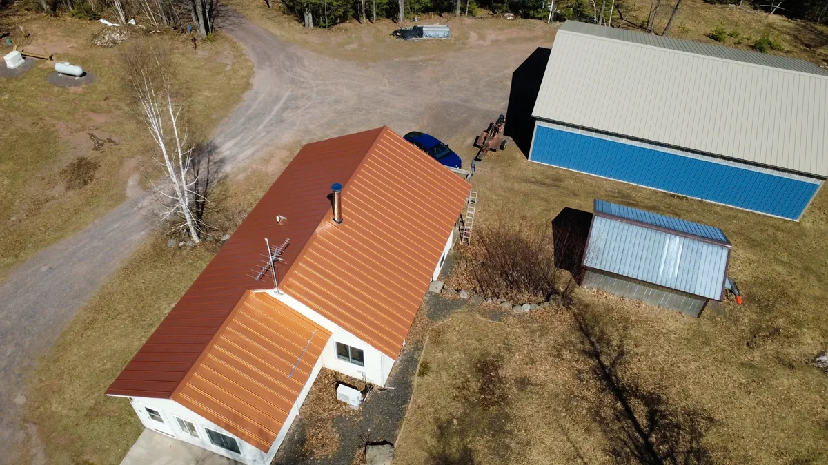 High overview of the homestead showing the orange roof and surrounding outbuildings