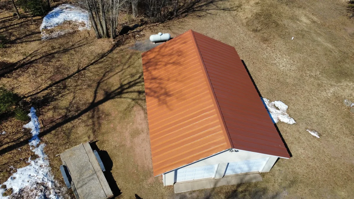 Top-down detail of the bright orange standing seam panels and ridge line