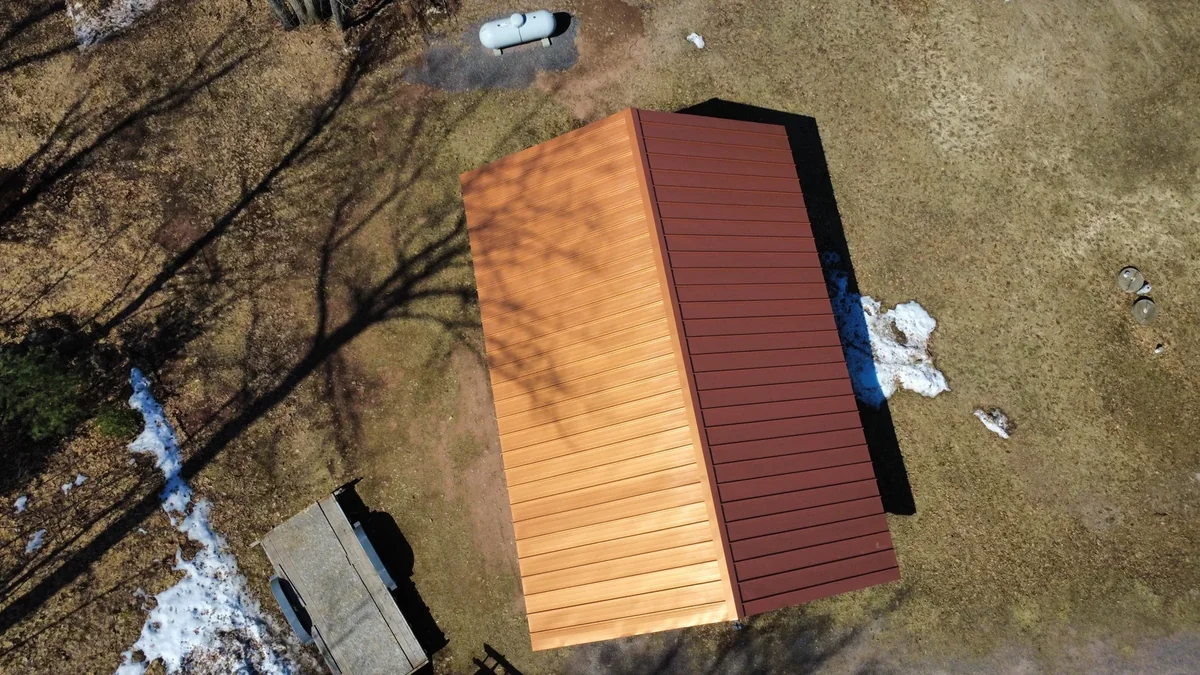 Angled overhead view of the orange metal roof against the brown spring yard
