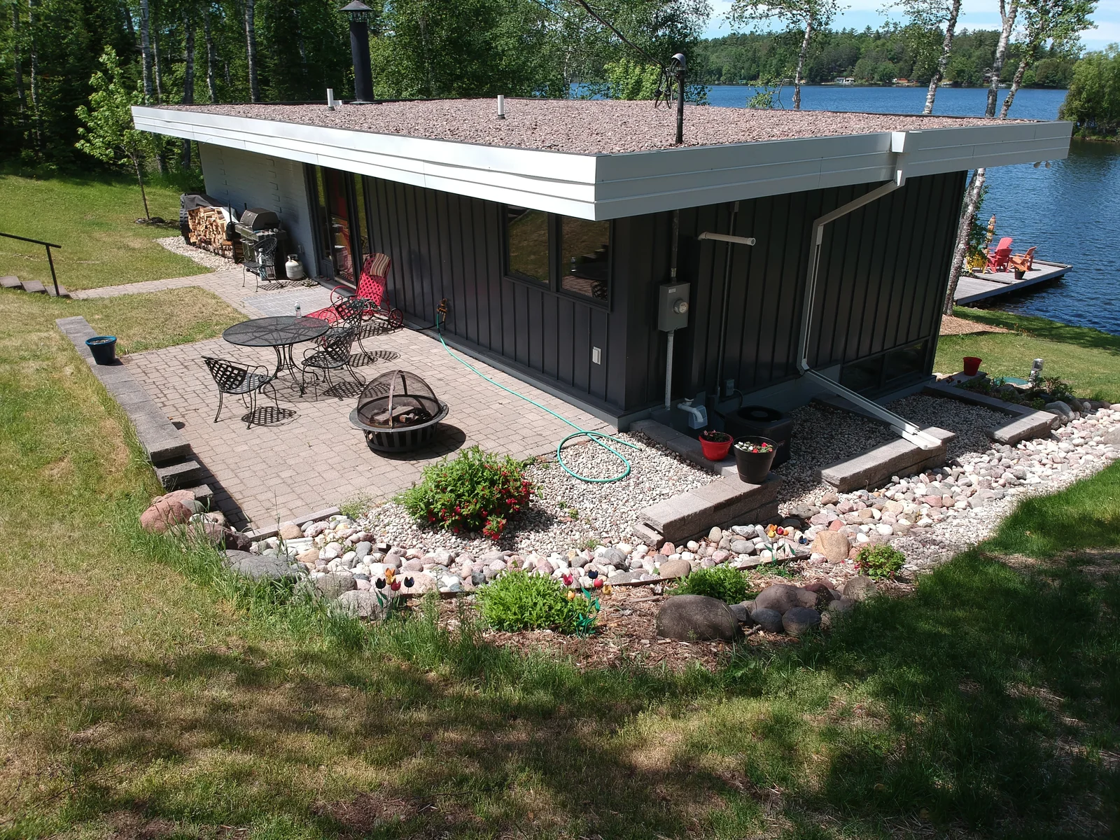 Low-angle view of the dark metal roof above the cabin's lakeside patio and stone fire area.