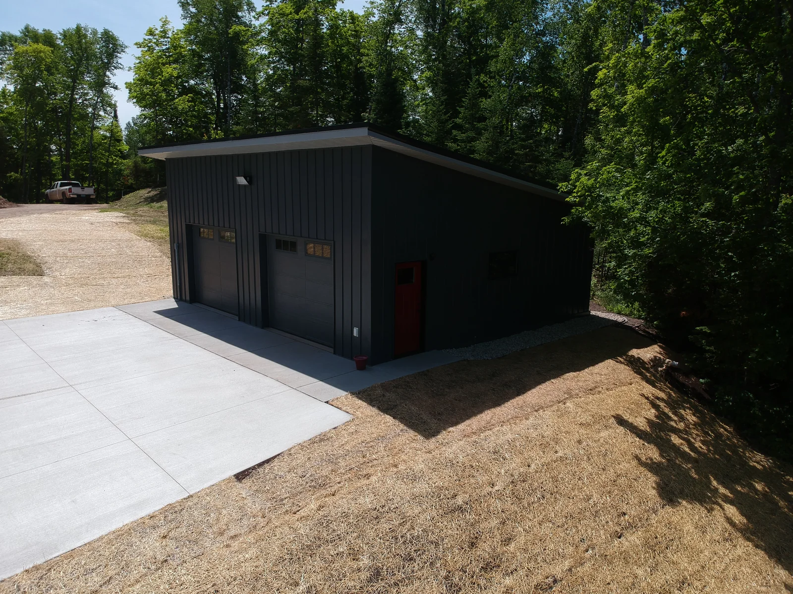 Corner gable of the matte black metal roof rising against the surrounding woods.