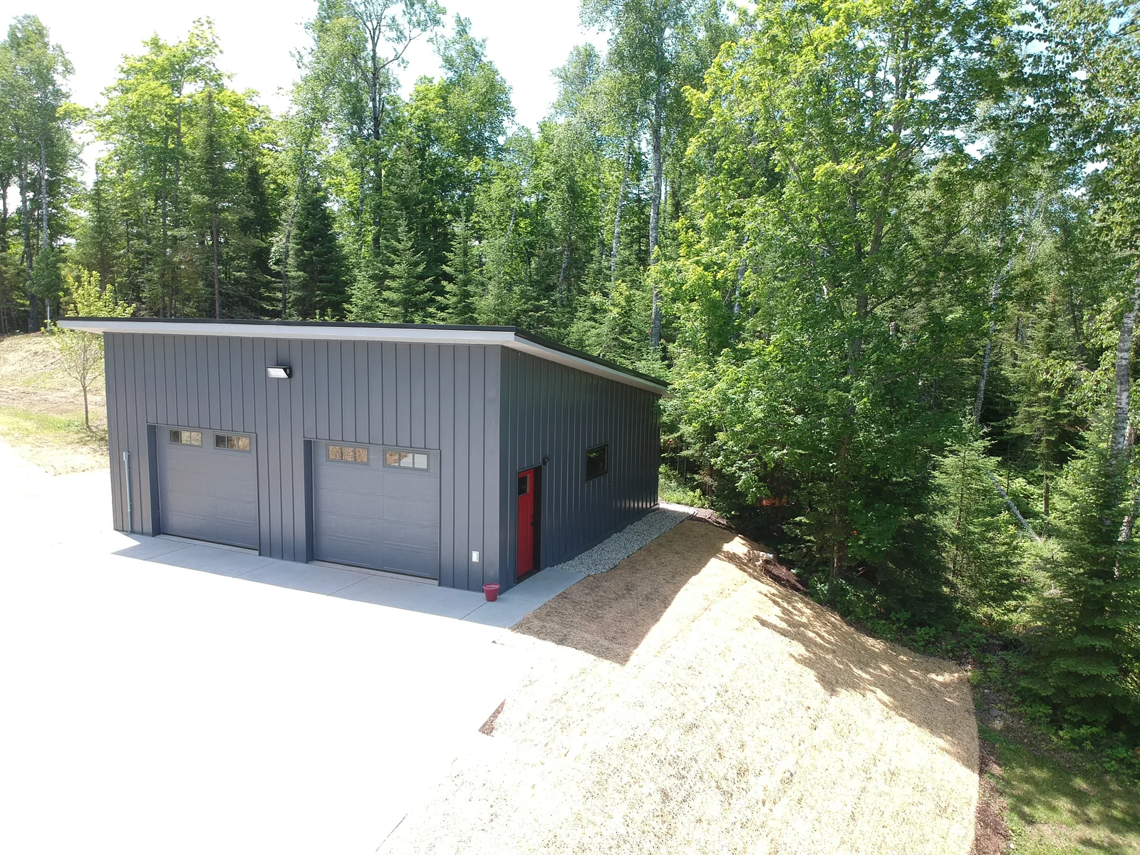 Front elevation showing the garage doors beneath the crisp black metal roofline.