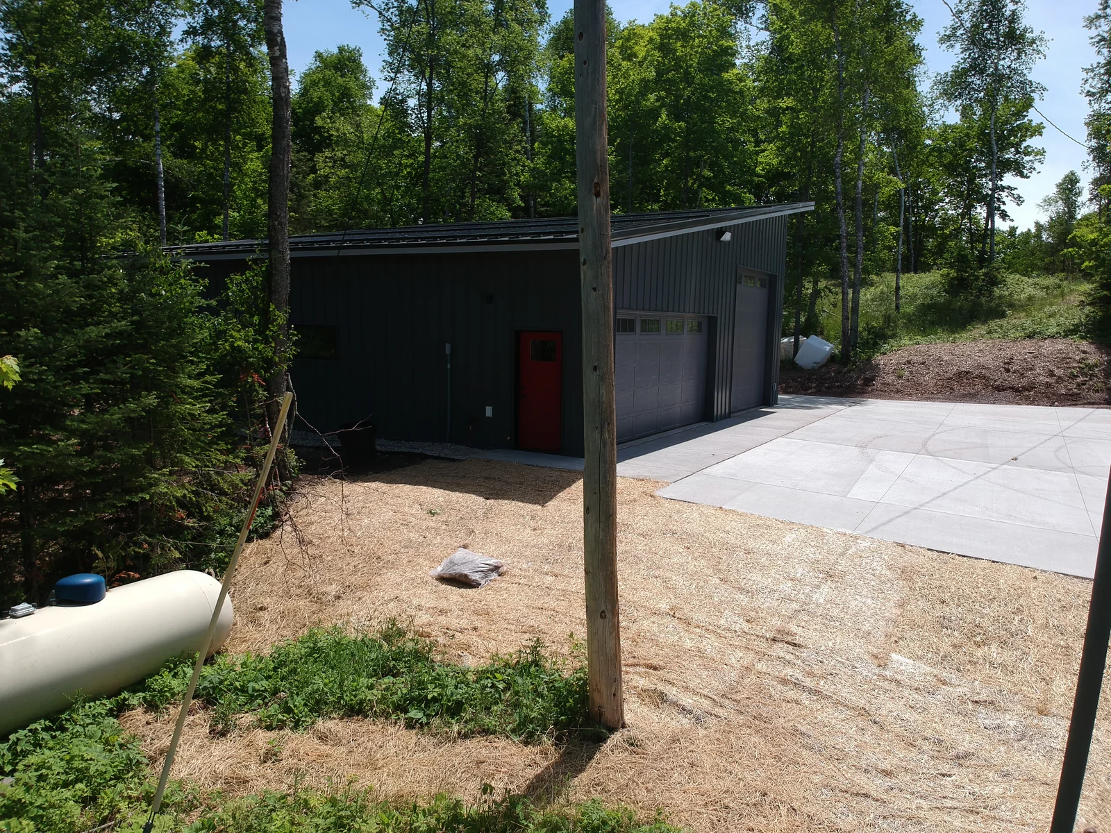 Rear approach to the building with the dark metal roof and a propane tank along the drive.