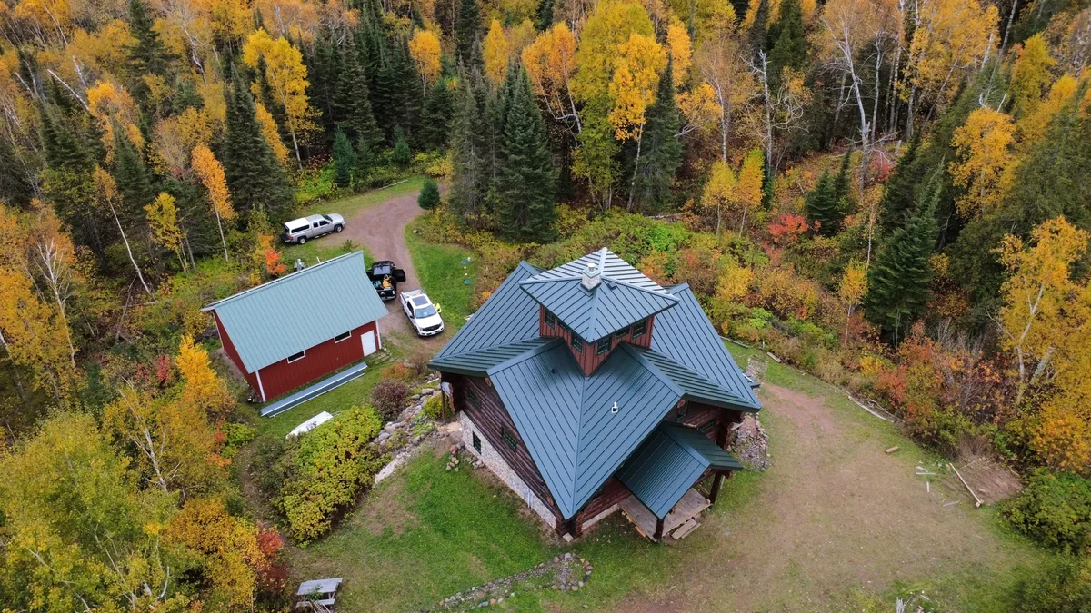 Overhead view of the multi-gabled grey metal roof surrounded by colorful trees