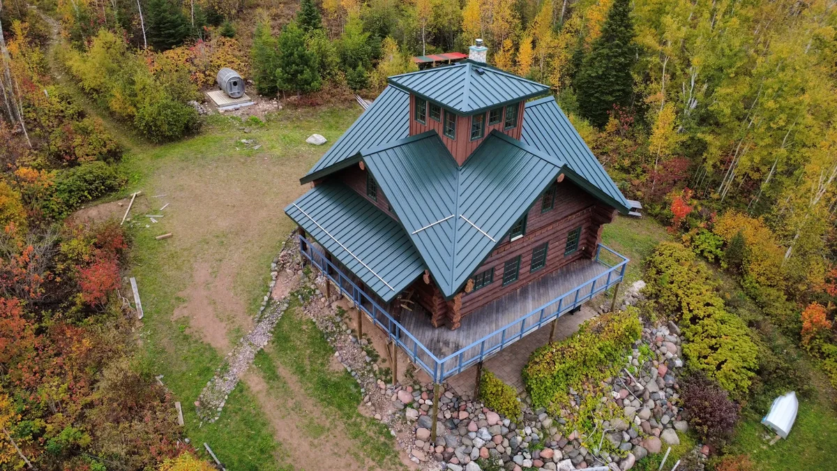 Close aerial of the grey metal roof peaks and the log walls of the lodge