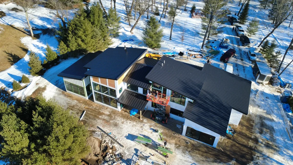 Sprawling charcoal metal roofline of a large home and attached shop seen from above.