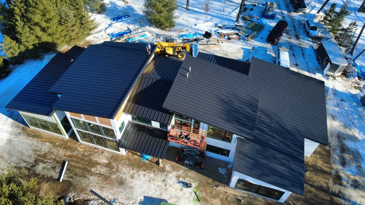Corner view of the dark-roofed structure with a lift parked alongside the new building.