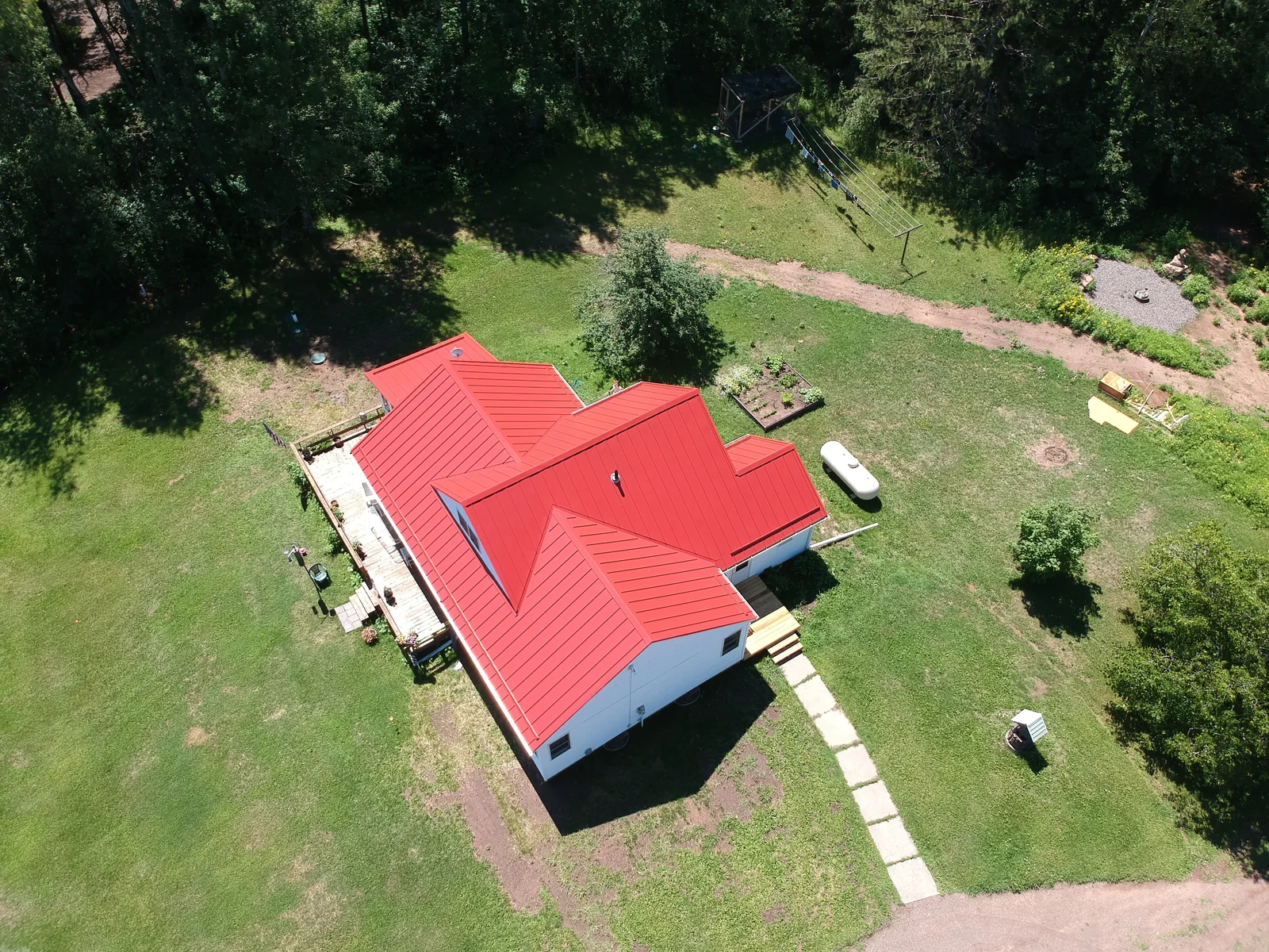 Drone shot of the red metal roof home with its detached garage and winding driveway