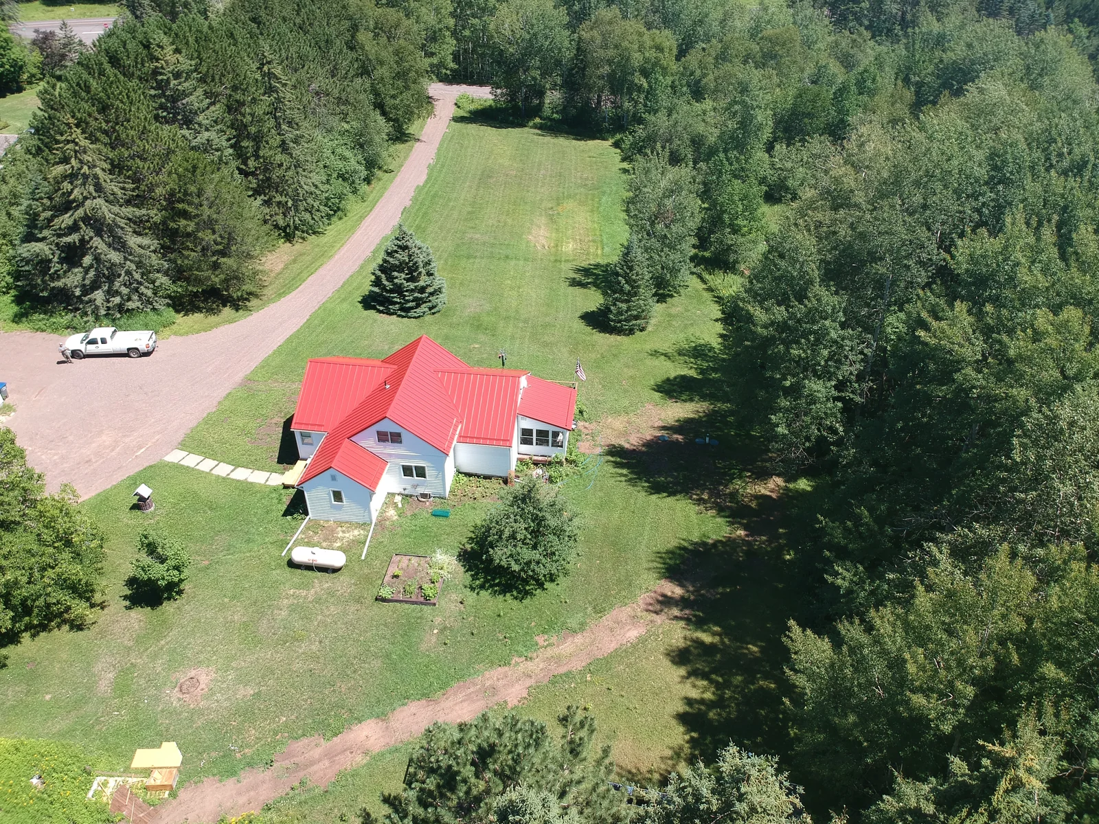 Distant aerial of the property showing the red metal roofs against the wooded hills