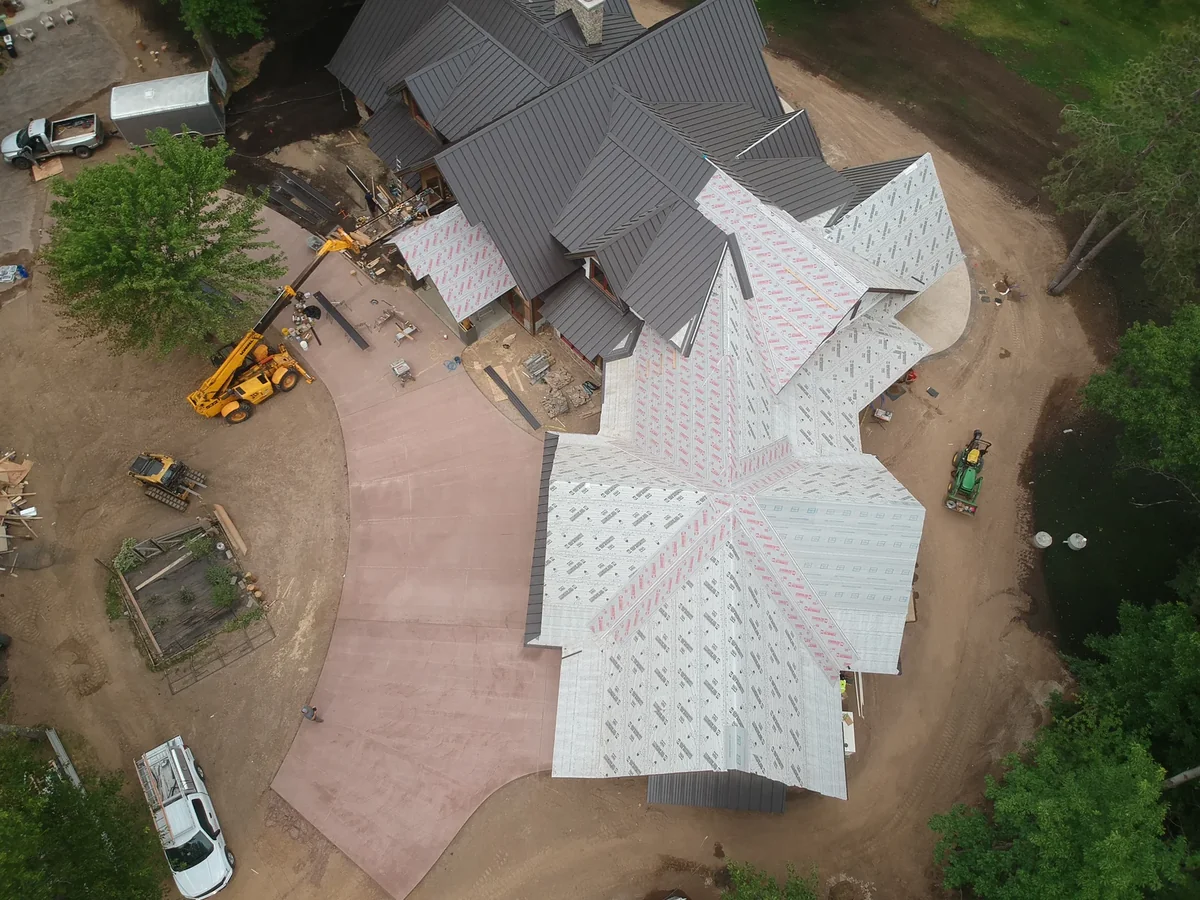 Overhead aerial of a large home mid-project with gray metal roofing and underlayment near Hayward, WI.