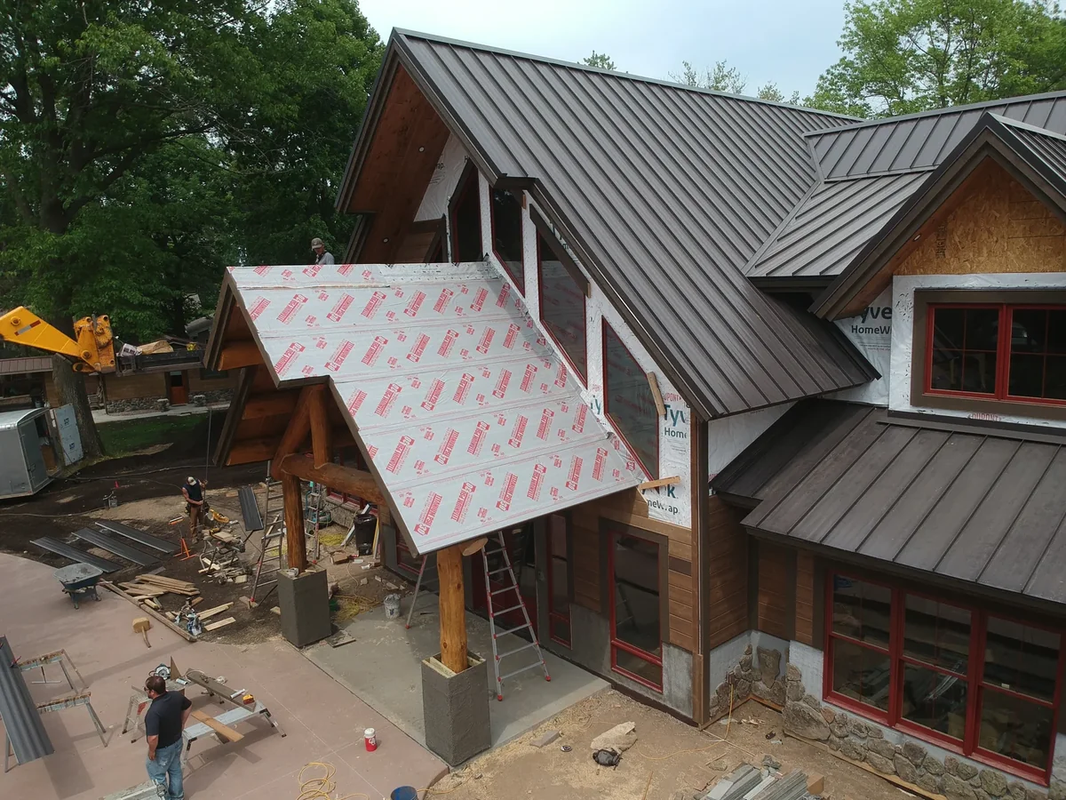Ground-level perspective of the timber-framed entry below the new metal roof.
