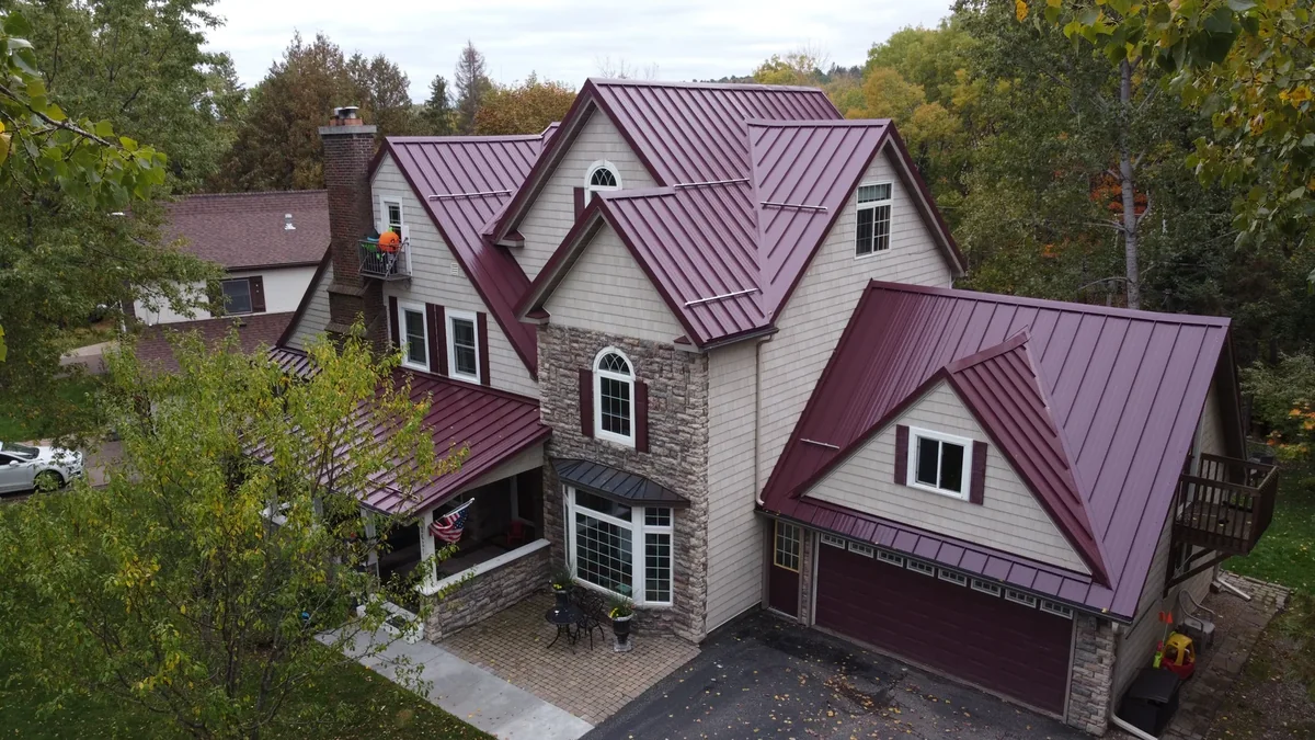 Aerial of the red-roofed home showing stone accents and a lower garage wing