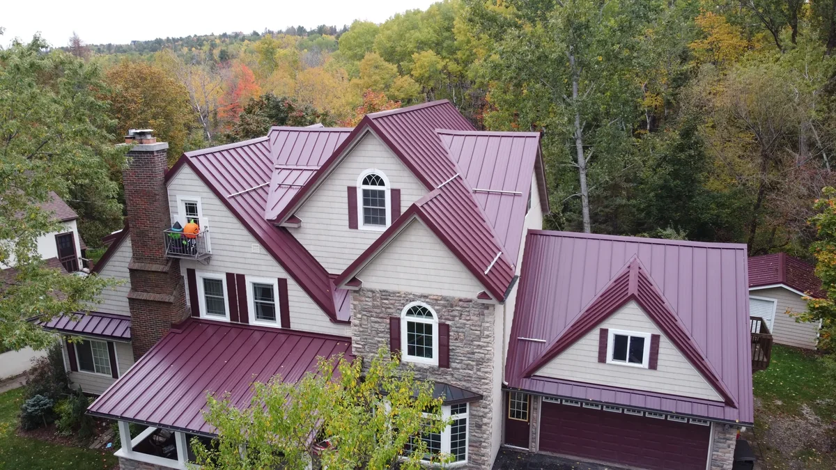 Angled view of the red metal roof over the stone-faced facade and dormers