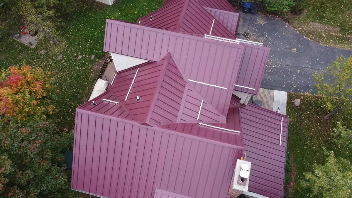 Top-down detail of the crimson standing seam panels and chimney
