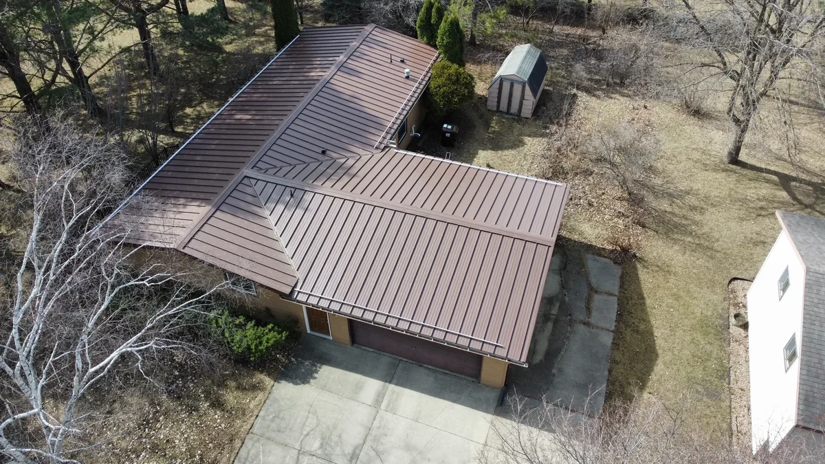 Long side view of the bronze metal roof stretching across the single-story home
