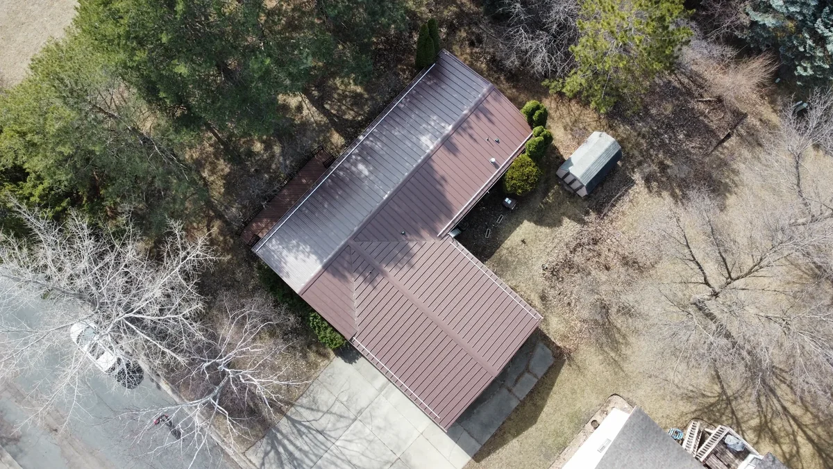 Top-down overview of the bronze roof and the home's footprint among bare trees