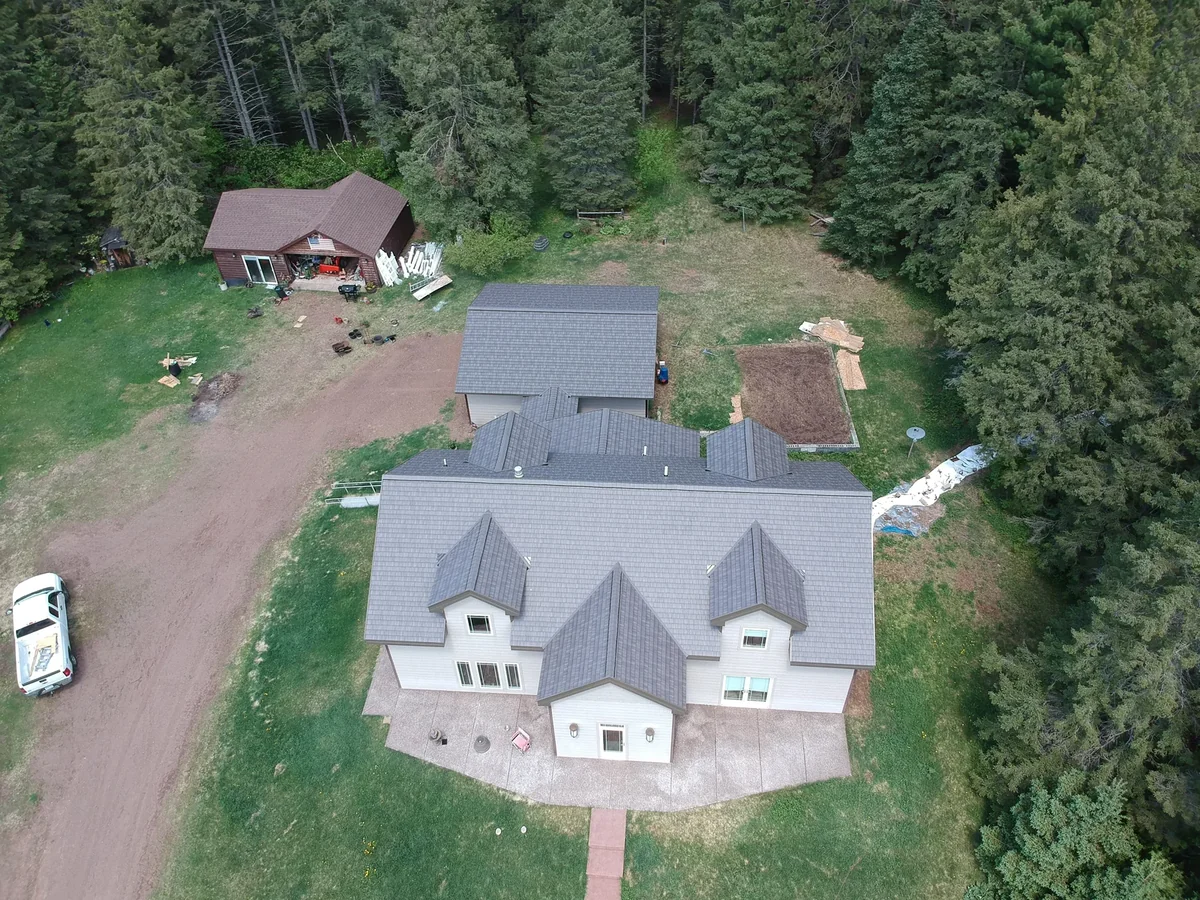 Front view of the gray metal shingle roof above the home and its winding driveway.