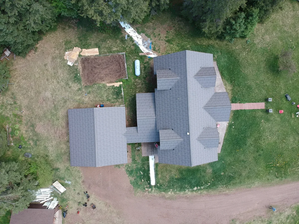 High overhead capturing the full layout of the gray metal shingle roof and its many gables.
