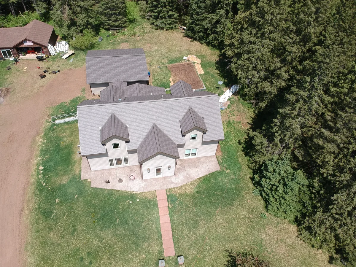 Front-quarter view of the gray home and matching metal shingle roof.